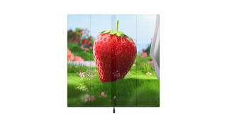 Ein halbtransparenter LED-Display zeigt eine Grafik einer Erdbeere die aufrecht auf einer grünen Wiese liegt. Auf der saftig grünen Wiese sind weitere Blumen sichtbar. Im Hintergrund befindet sich ein Erdbeerstrauch der noch weitere Früchte trägt.